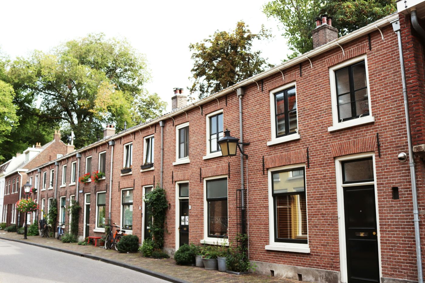 Een rij bakstenen rijtjeshuizen in een Nederlandse straat.