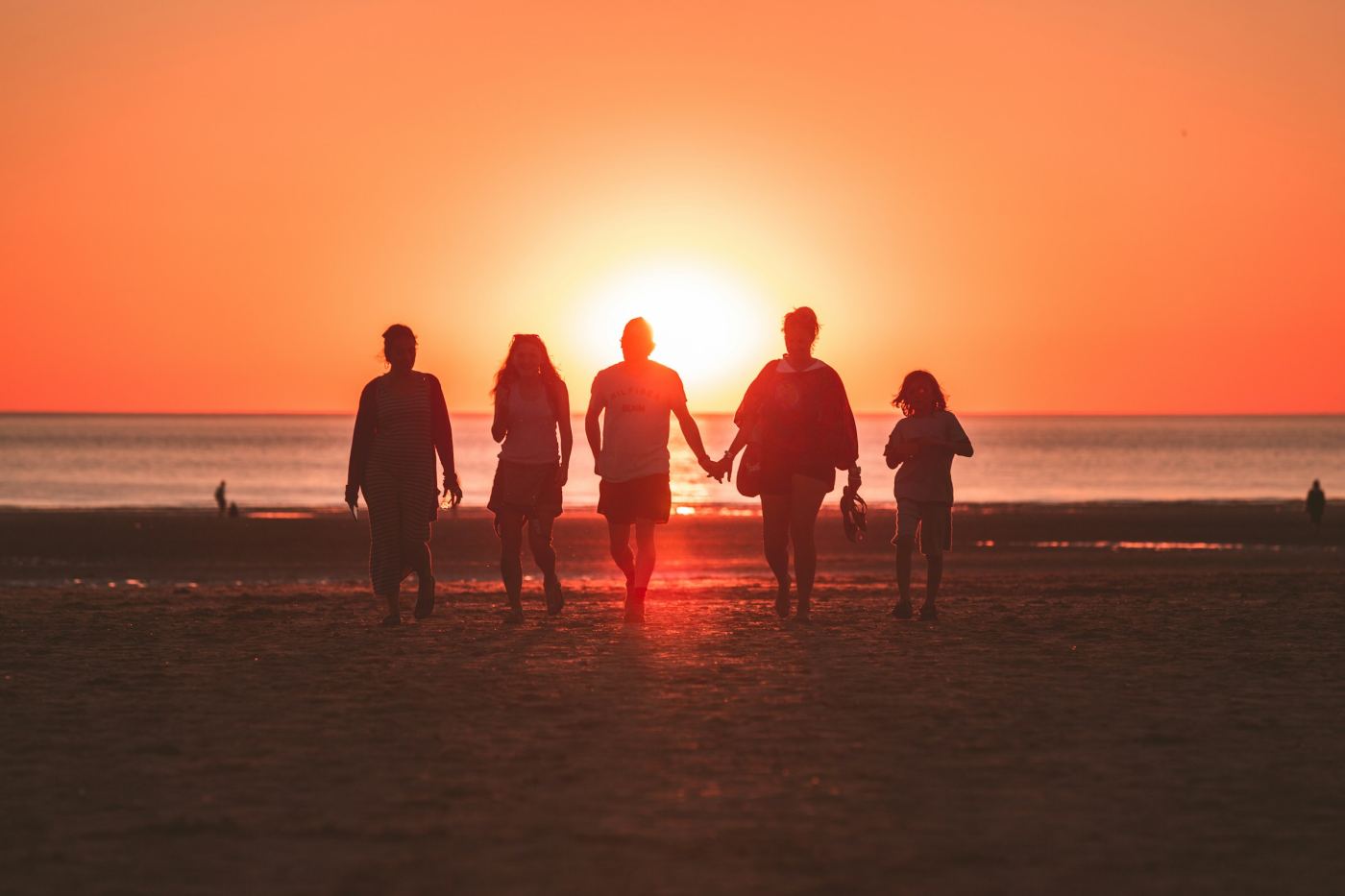 Silhouet van een gezin op het strand bij zonsondergang.